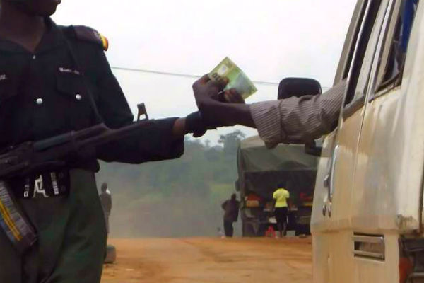 A Nigerian police officer collects N20 from a driver