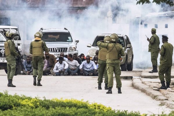 Zanzibar's anti-riot police officers stand gaurd by a group of men sitting on the ground during an operation after the opposition called for protests in Stone Town, on October 29, 2020 as tensions rise while the results of the general election are being announced.