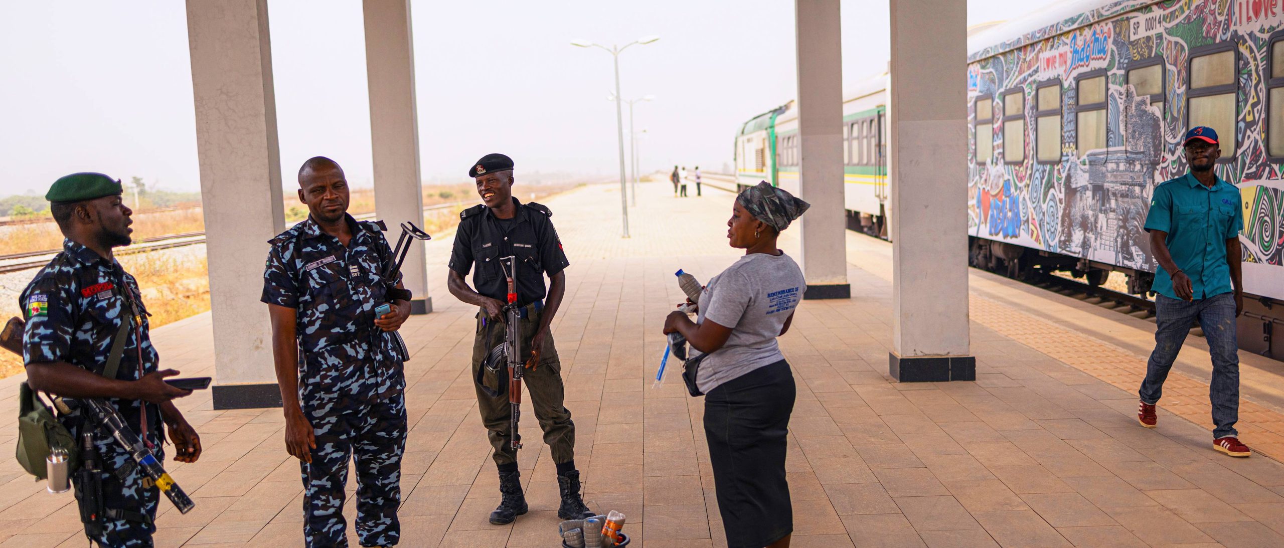 Members of the Nigerian Mobile Police (MOPOL) talking to a cleaner at the Idu Railway Station.