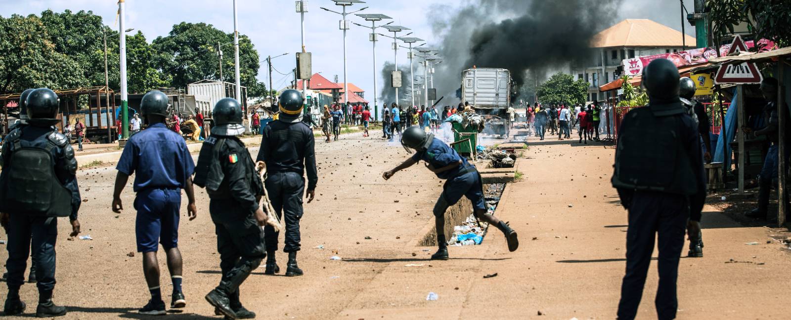A police officer throws a stone at demonstrators during a protest in Conakry, Guinea. (Photo: John Wessels/AFP)
