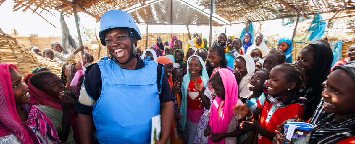 Un officier de police ghanéen, membre de la MINUAD, avec des écoliers dans le camp de déplacés d’El Sereif, au Darfour-Sud.