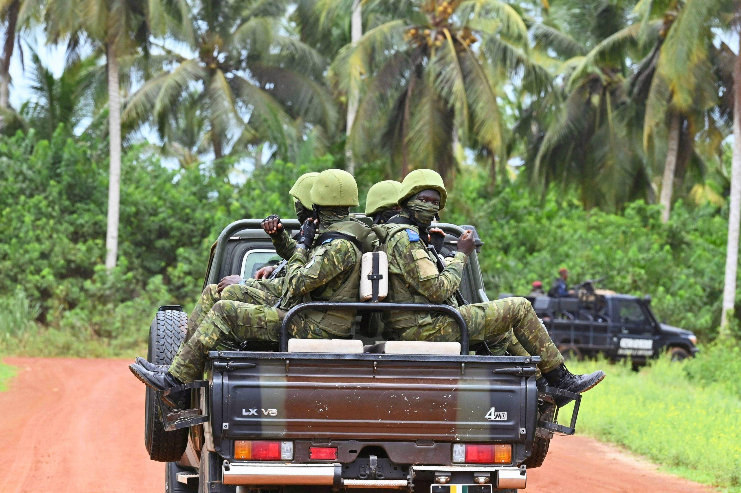 Ivorian soldiers ride on the back of a vehicle. 