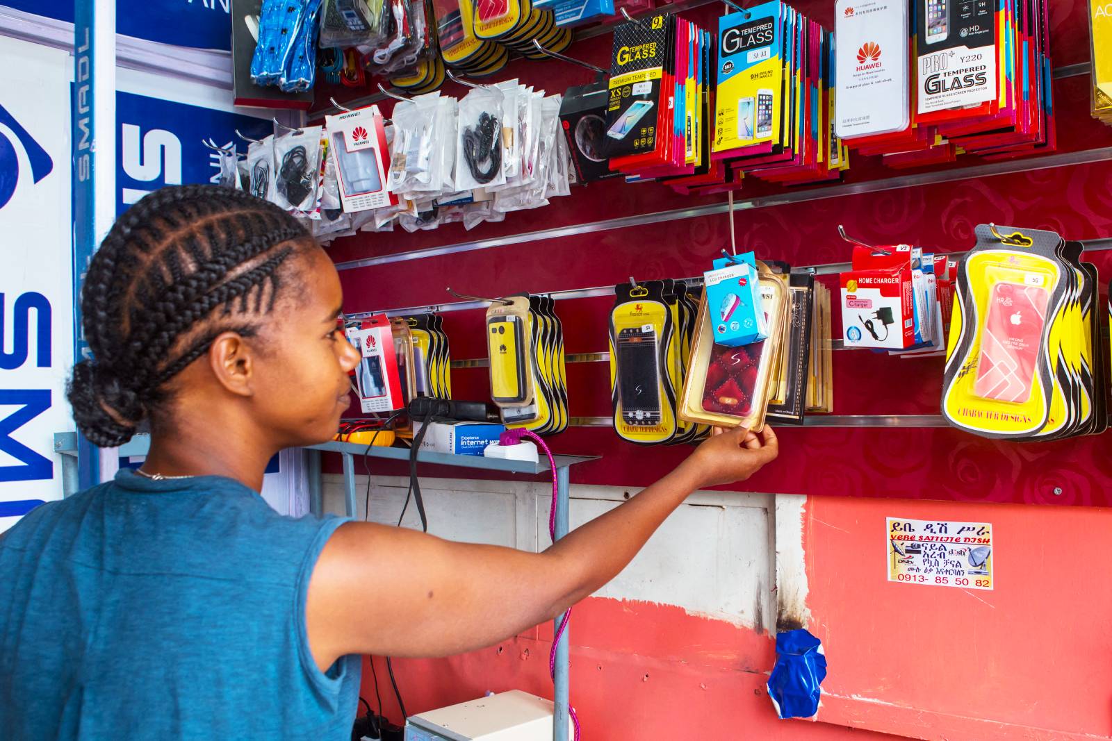 A girl looking at a wall of mobile products.