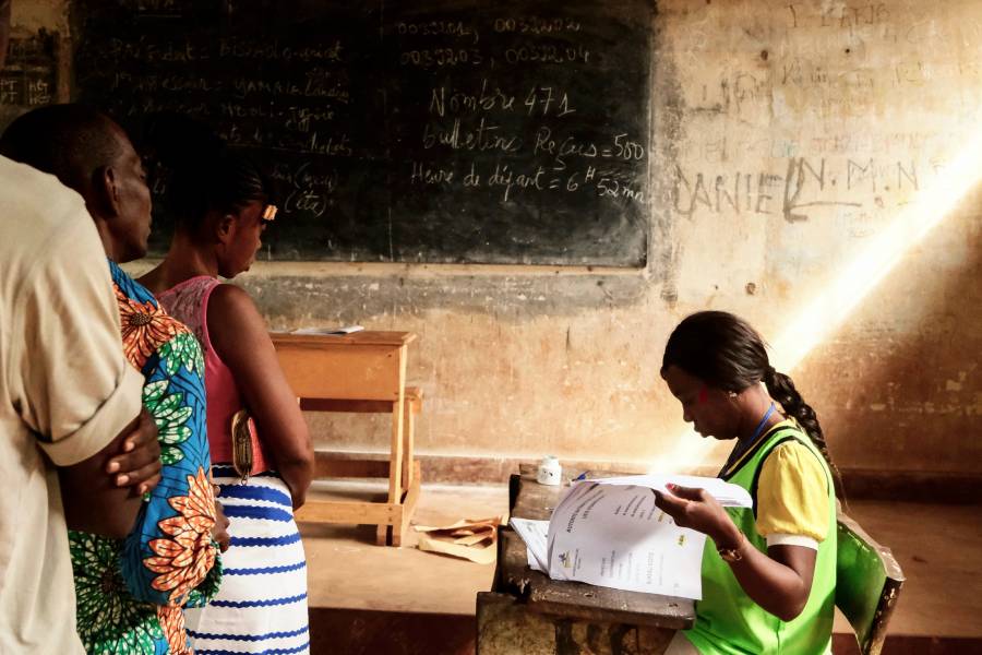 Voters wait as a electoral commission official checks a voter's roll at the polling station in Bangui. (Photo: AFP/Camille Laffont)