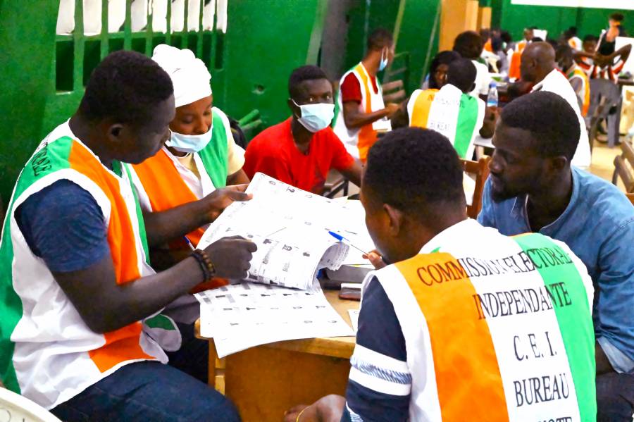 Electoral commission officials check the voter's roll as they count votes at a polling station in Abidjan on October 31, 2020. (Photo: AFP/Issouf Sanogo)