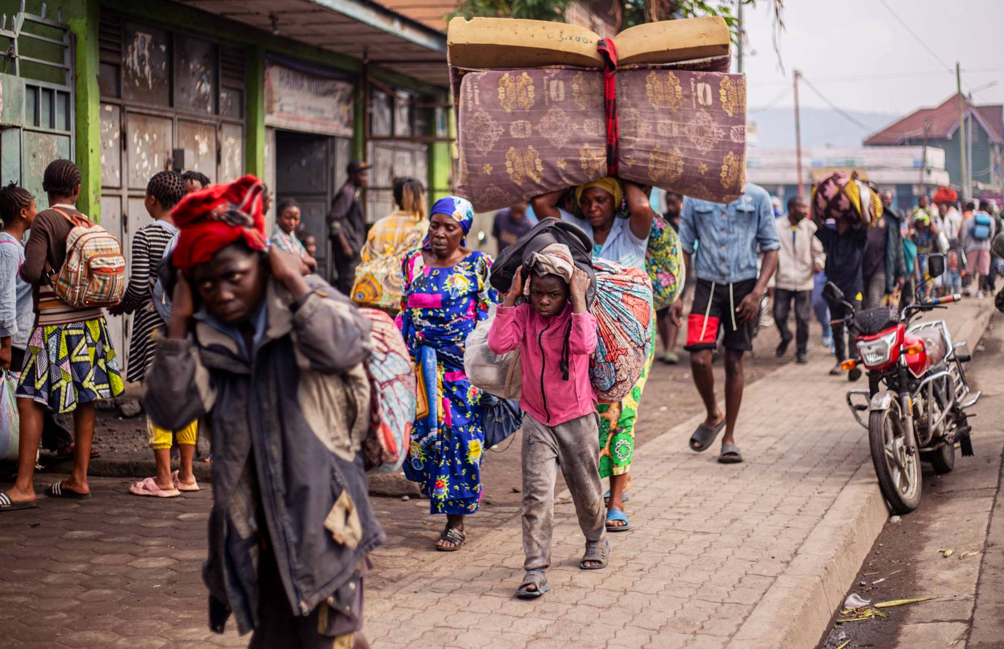 Congolese walking down a street in Goma carrying their belongings.