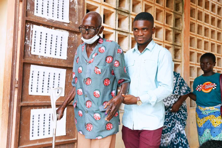 A man walks an elder to a polling station at the Agbalepedogan public primary school in Lomé. (Photo: AFP/Emile Kouton)