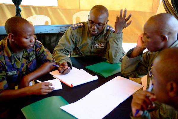 Four KDF airmen around a table talking and taking notes