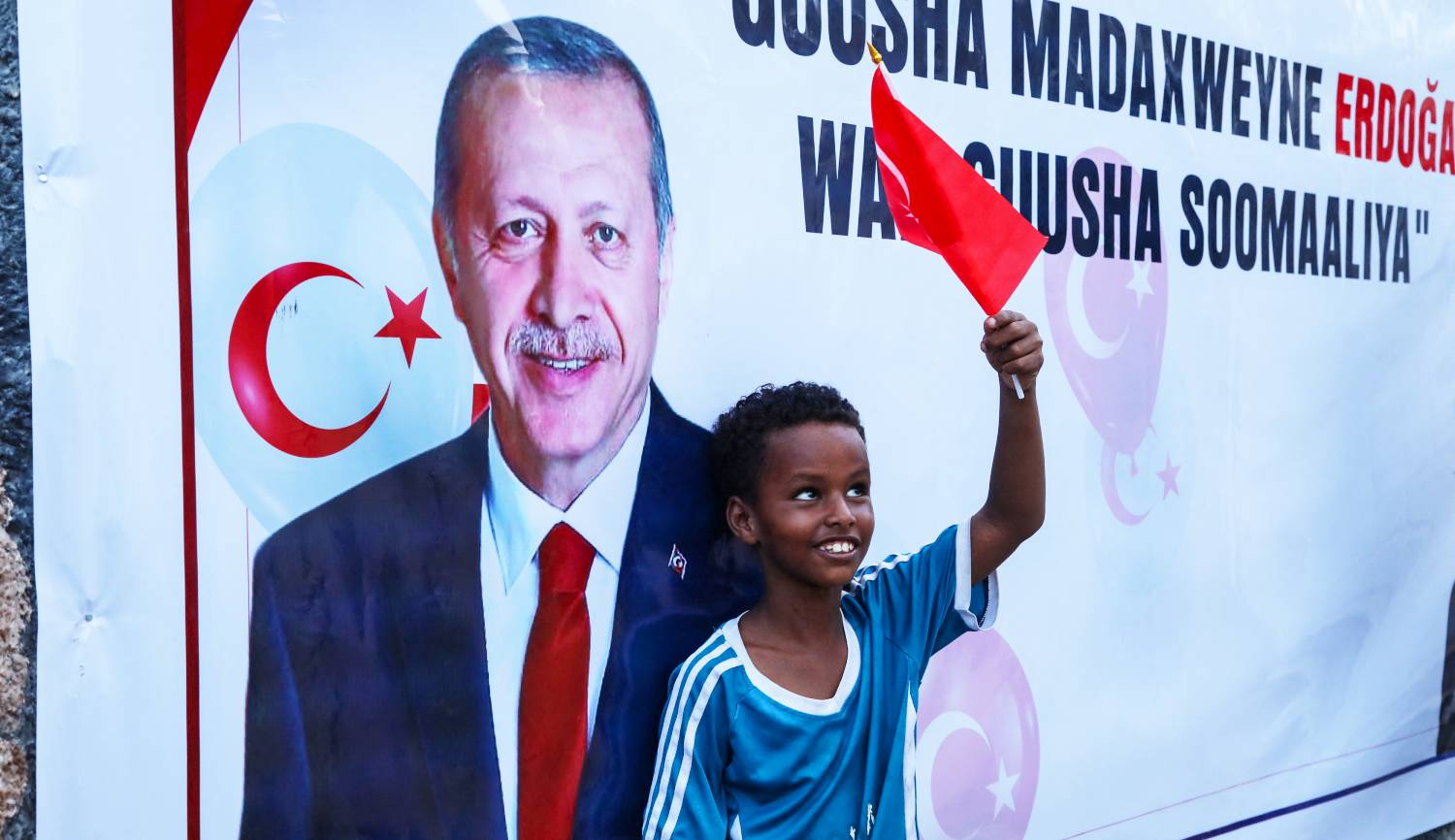 Somali Boy with Turkish Flag A Somali boy holds a Turkish national flag in front of a large banner of Turkish President Erdogan