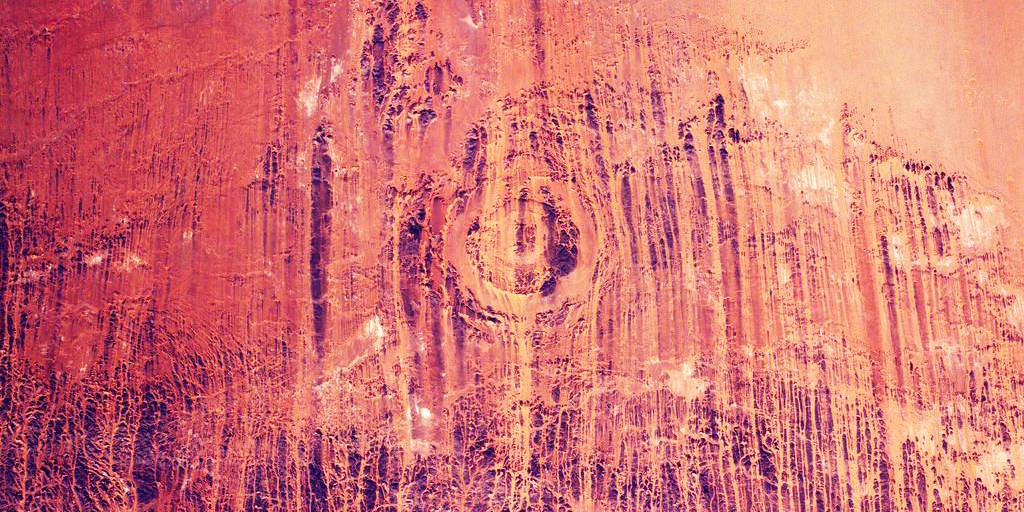 An aerial view of the desert showing dozens of vertical streaks of blown sand.
